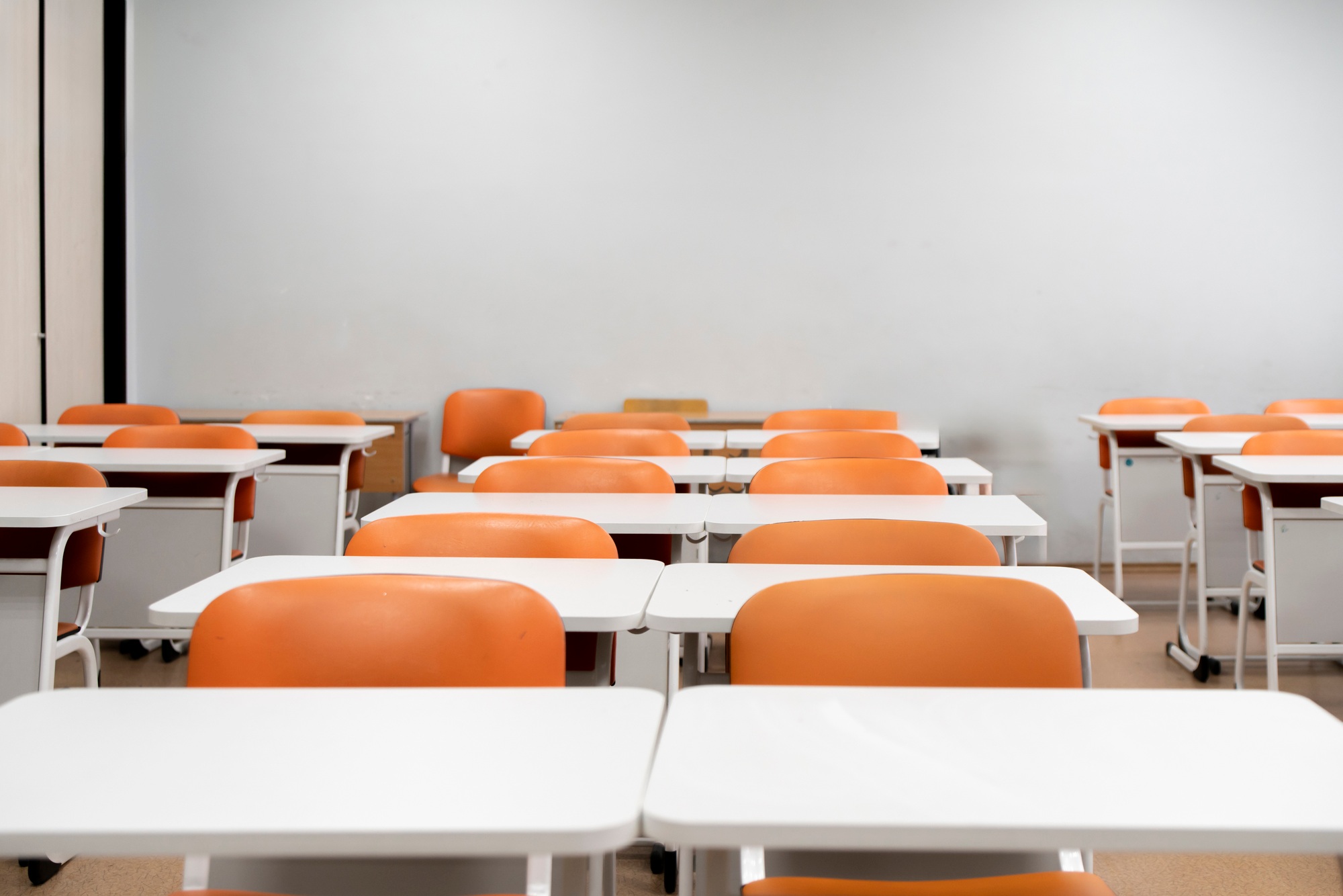 a back to school concept, empty classroom with white tables and chairs